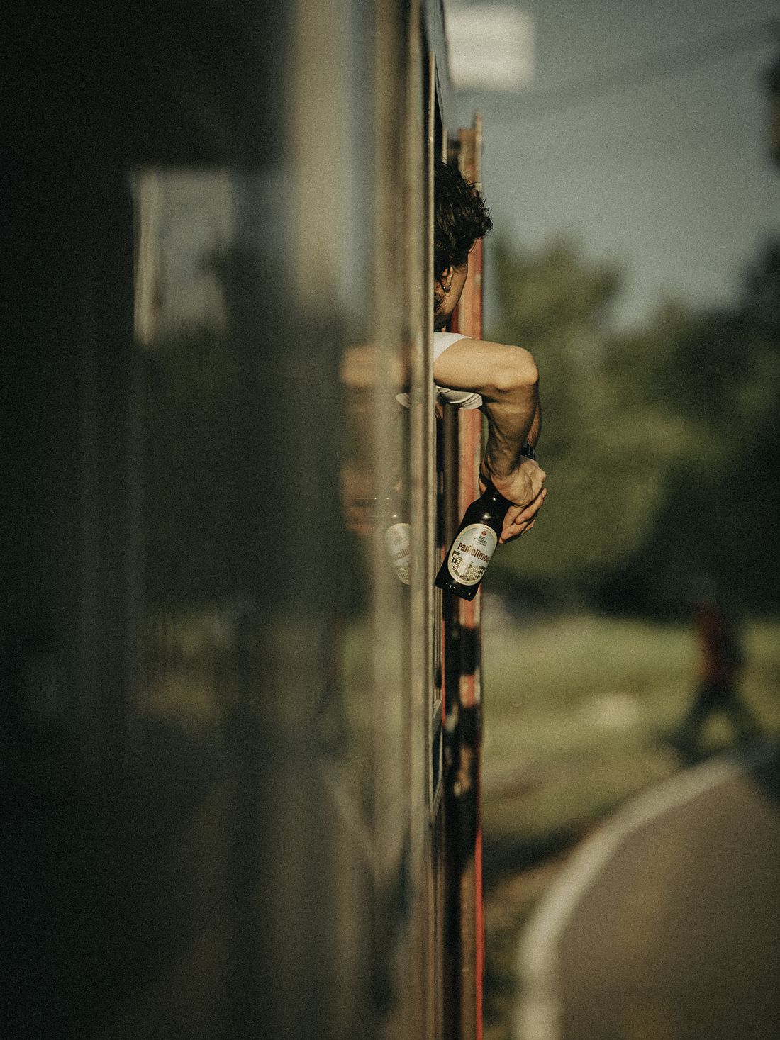 O mână ține o sticlă pe geamul unui tren în mers